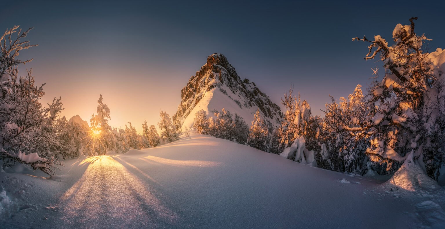 sunset glow hitting a mountain thats partly covered with snow