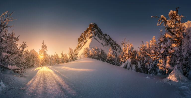 sunset glow hitting a mountain thats partly covered with snow